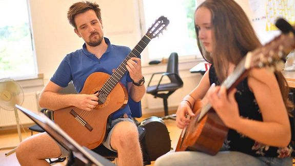 Eine junge Frau und Mann musizieren mit Gitarren