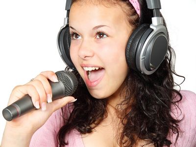 Jugendliche singt mit Mikrofon und Kopfhörern