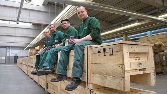 Arbeiter sitzen auf Holzkisten im Lager und machen Pause 