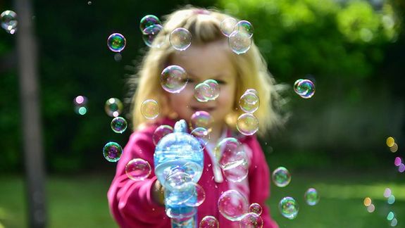 Kleines Mädchen spielt mit Seifenblasen